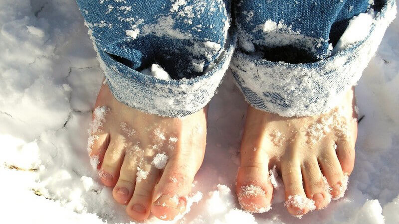 Nackte Füße im Schnee, unterer Teil der Jeans mit Schnee voll