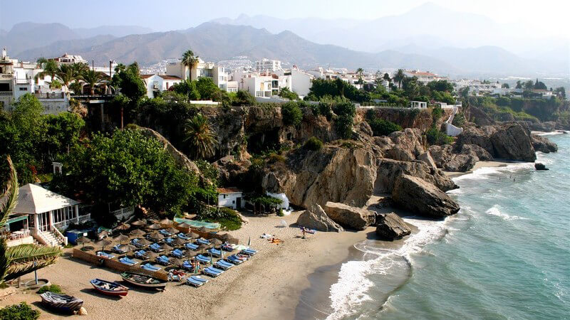 Strand in Andalusien mit Liegen, umgeben von Felsen