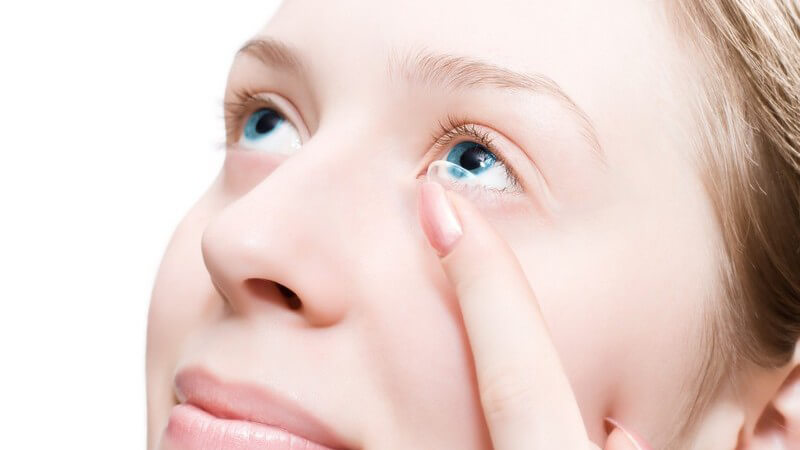 Nahaufnahme junge Frau setzt Kontaktlinse in linkes Auge