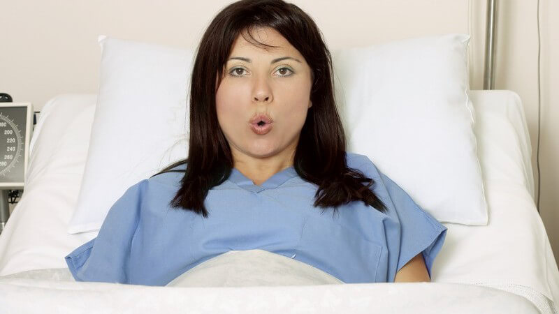 Schwangere Frau im Krankenbett macht Atemübungen