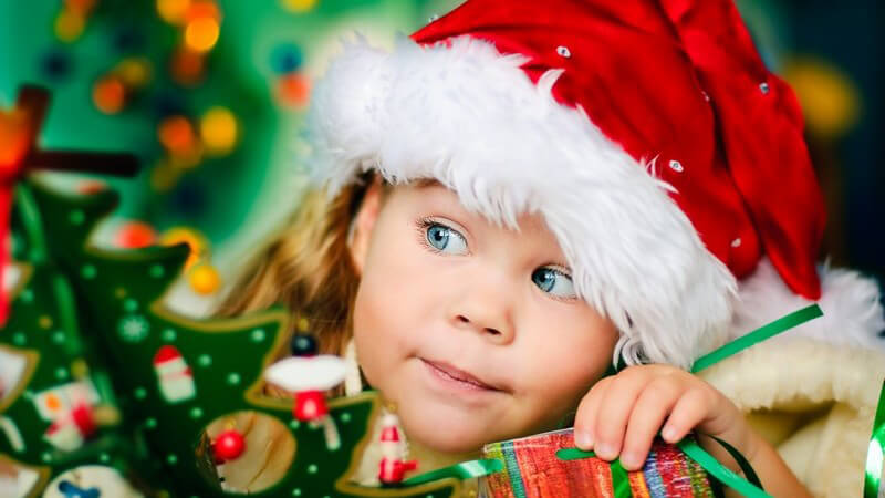 Kleines neugieriges Mädchen mit Weihnachtsmannmütze