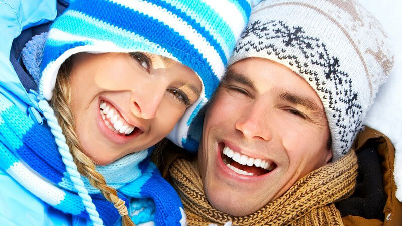 Junges Paar in Winterkleidung lächelt in Kamera