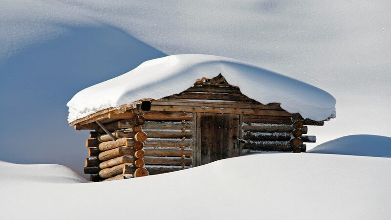 Eingeschneite Skihütte in Schneelandschaft