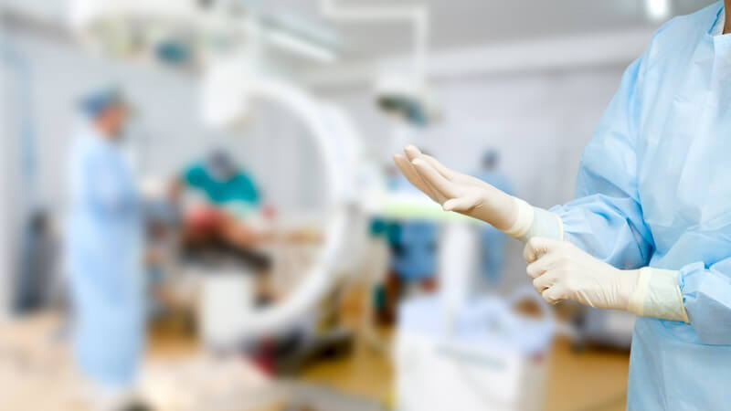 Ärztin zieht Handschuhe an, Vorbereitung auf Operation