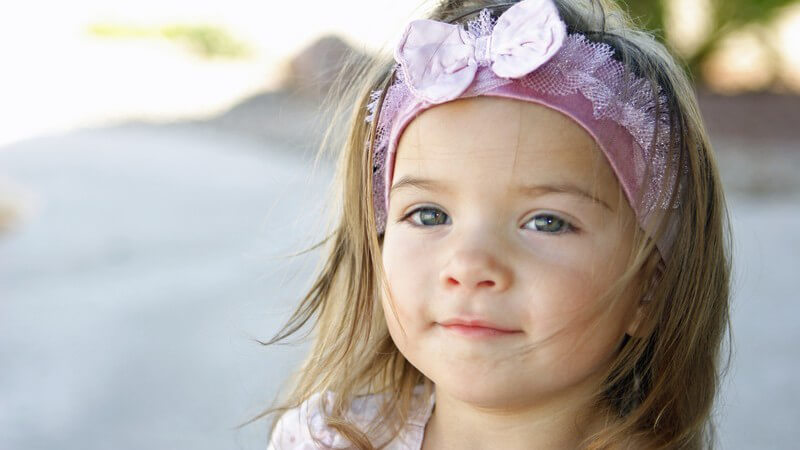 Kleines lächelndes Mädchen mit Schleife im Haar