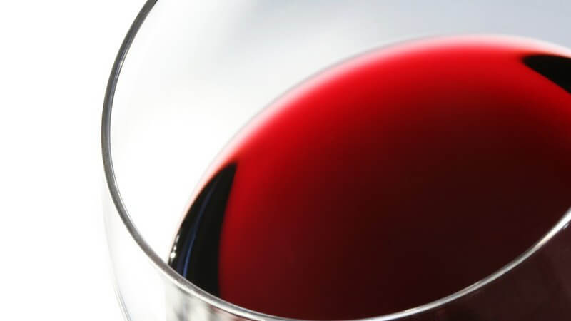 Nahaufnahme Rotwein in Rotweinglas vor weißem Hintergrund