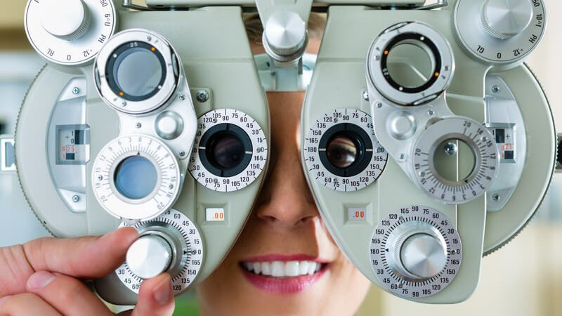 Sehtest beim Augenarzt oder Optiker: Frau am Phoropter