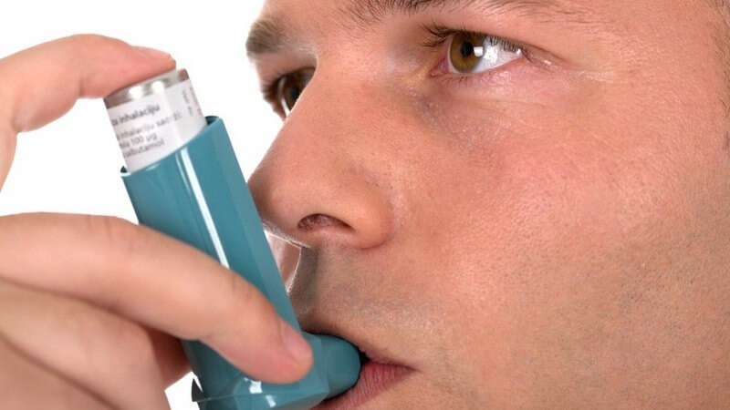 Asthma - Mann mit Asthmaspray im Mund