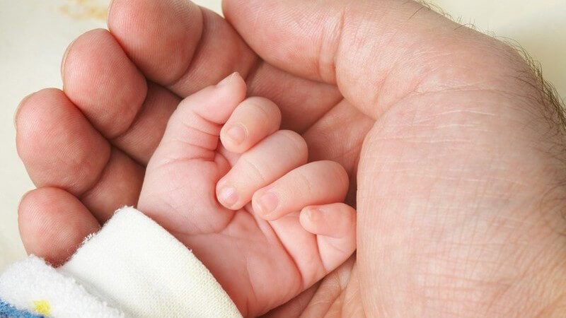 Männerhand, in der eine Baby-Hand liegt
