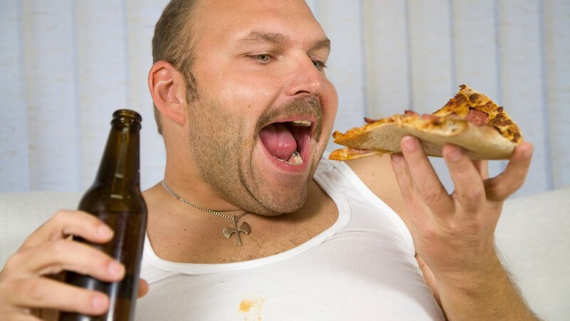 Übergewichtiger Mann in weißem Unterhemd mit Pizza und Flasche Bier