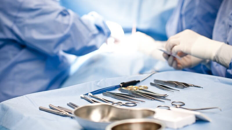Operationsbesteck im OP-Saal, im Hintergrund Chirugen bei Operation