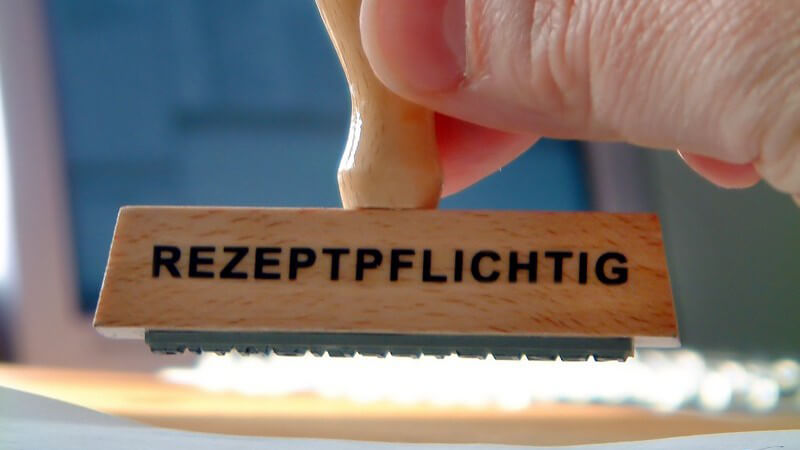 Holzstempel mit Schriftzug "Rezeptpflichtig" wird benutzt