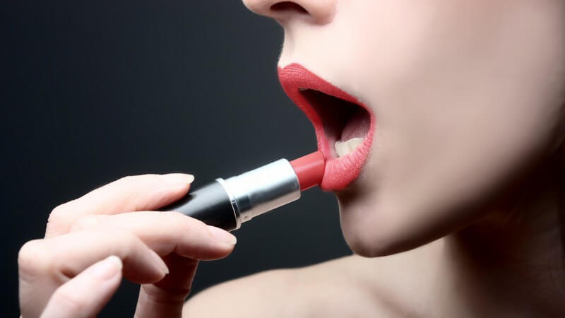 Nahaufnahme junge Frau trägt roten Lippenstift auf