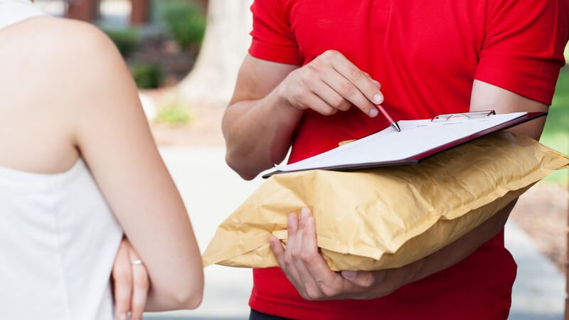 Paketdienst - Postbote bringt Päckchen und bittet um Unterschrift