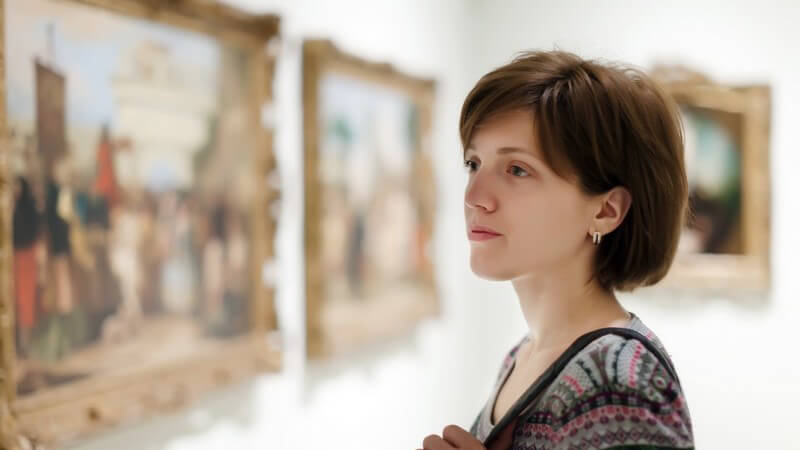 Frau schaut sich Bilder im Museum oder in einer Kunstgalerie an
