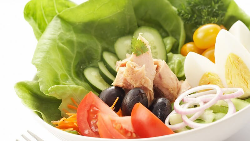Nahaufnahme frischer grüner Salat mit Thunfisch, Gurken, Tomaten, Oliven etc.