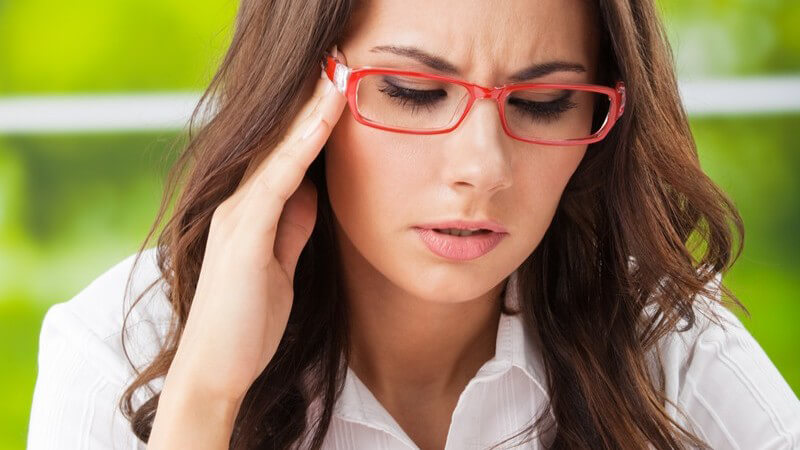 Müde, gestresste Geschäftsfrau mit Kopfschmerzen fasst sich an die Schläfe