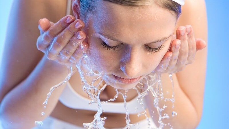 Junge Frau vor Schüssel mit Wasser wäscht sich das Gesicht
