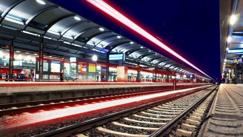 Beleuchteter Bahnhof bei Nacht, Blick auf Schienen