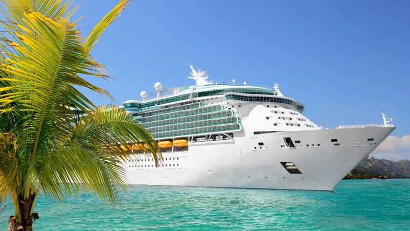 Luxus Kreuzfahrtschiff fährt vom Hafen ab, im Vordergrund Palme, türkises Meer