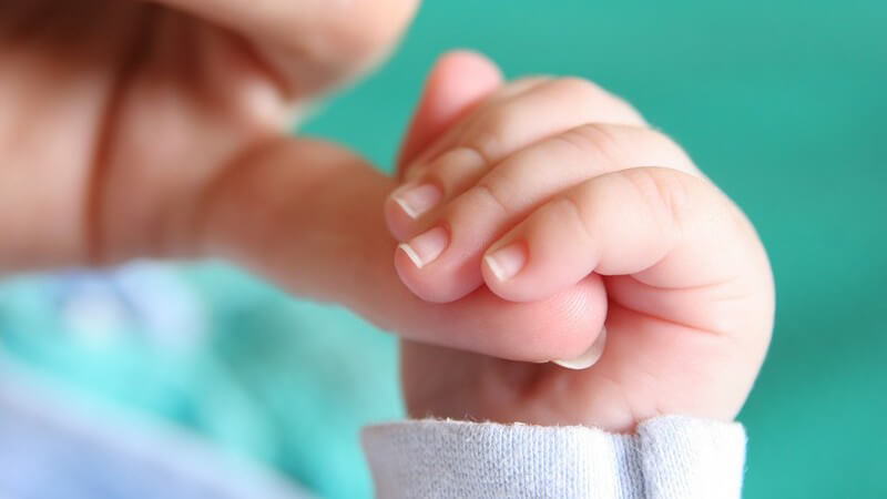 Babyhand hält Finger der Mutter fest