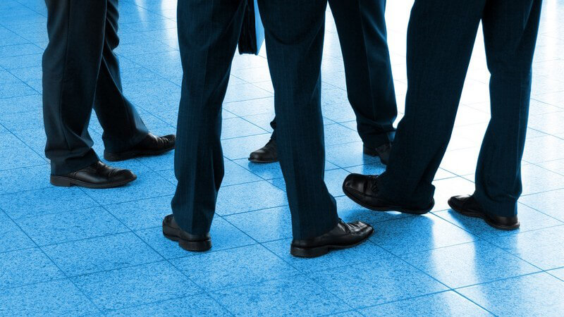 Vier Paar Beine von Geschäftsmännern im Anzug