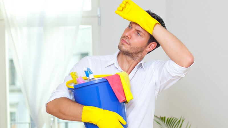 Hausmann mit Handschuhen, Eimer und Putzmitteln nach getaner Hausarbeit