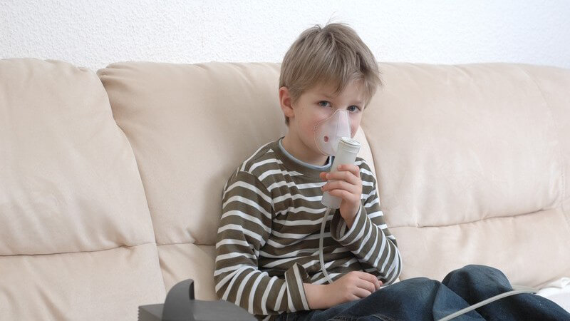 Kleiner Junge auf Couch mit Inhaliergerät, Allergie