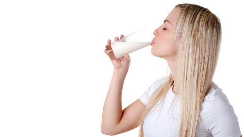 Junge blonde Frau trinkt Milch aus Glas