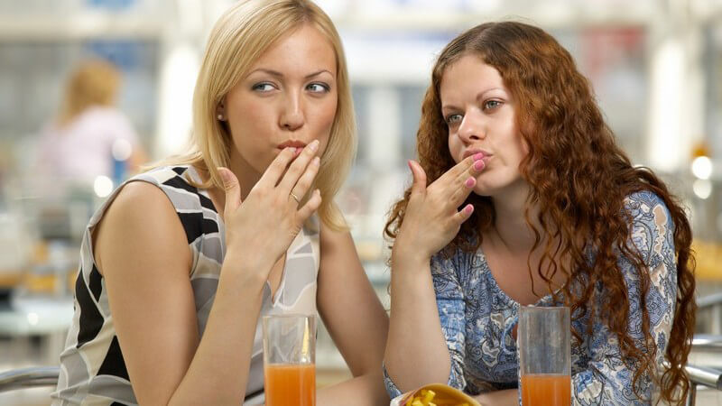 Zwei Freundinnen im Café lecken sich die Finger