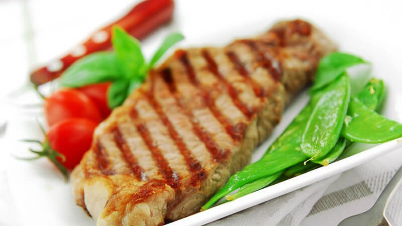 Gegrilltes Steak auf weißem Teller mit Salat und Tomaten