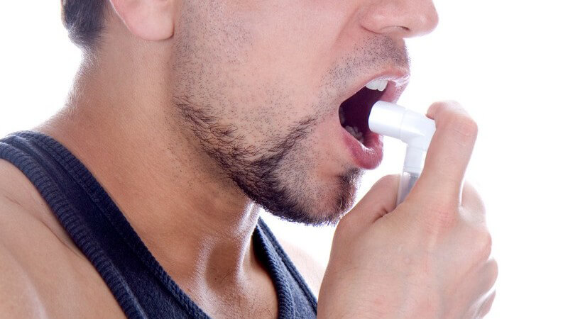 Nahaufnahme Mann hält Beatmungsgerät vor Mund, Asthma