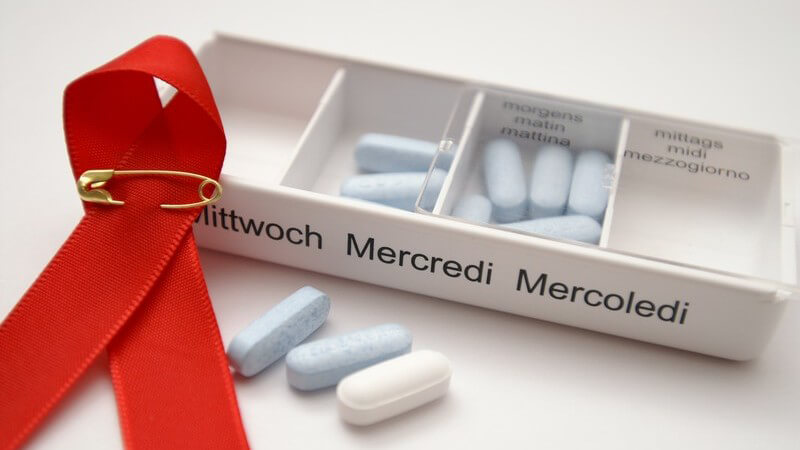Nahaufnahme AIDS Schleife neben Schachtel mit Pillen für Mittwochs, 3x täglich