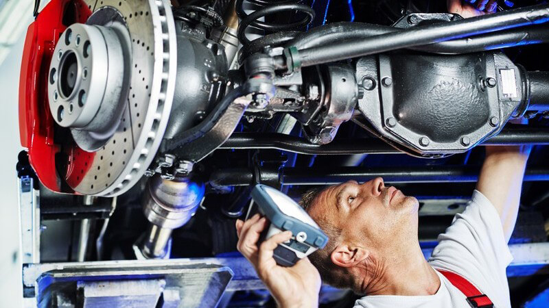 Automechaniker in Werkstatt überprüft Motor eines Autos