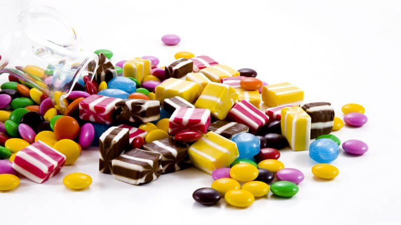 Auswahl an Süßigkeiten (Smarties, Bonbons) auf weißem Hintergrund