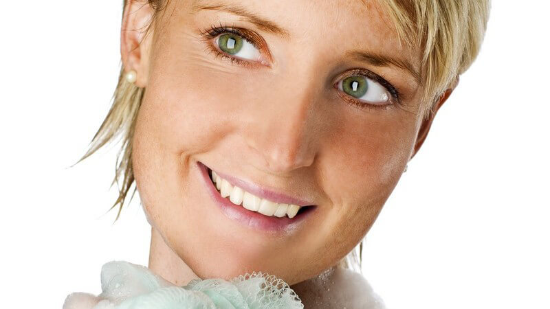 Blonde kurzhaarige Frau eingeschäumt unter Dusche mit Schwamm