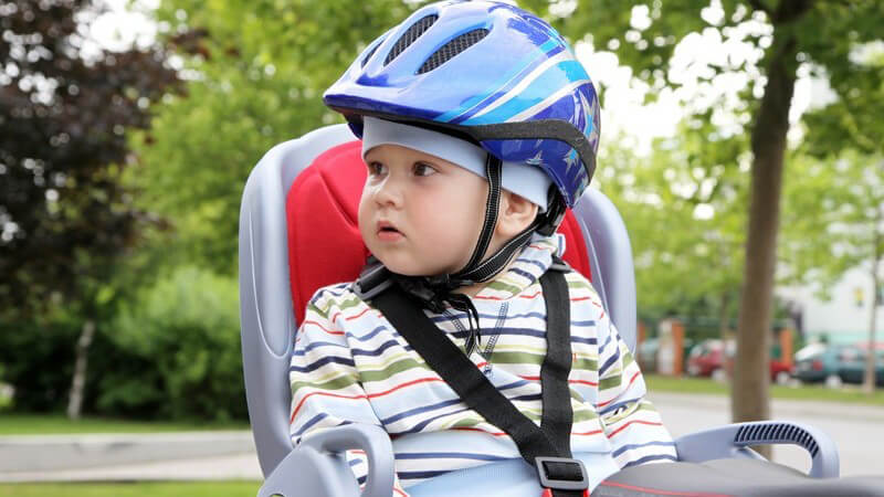 Kleinkind mit Fahrradhelm sitzt im Fahrradsitz