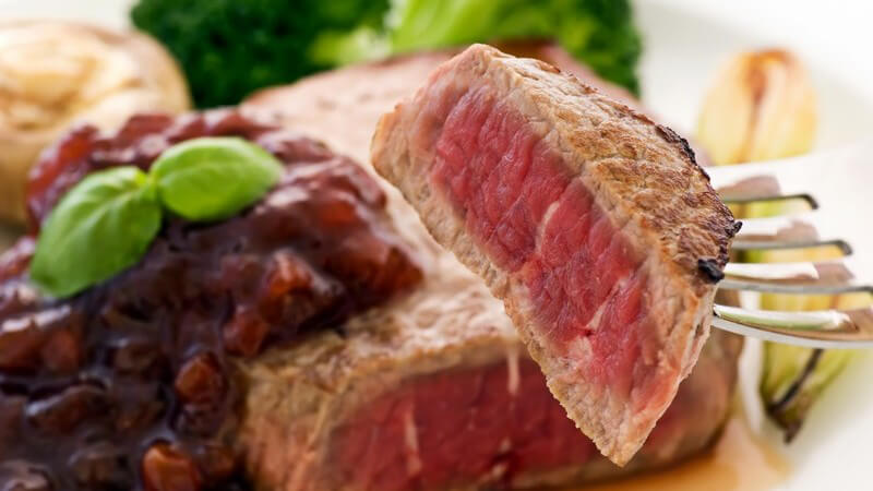 Steak auf Gabel, mit Preiselbeersoße und Brokkoli serviert