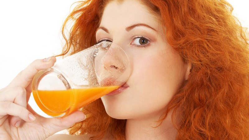 Junge rothaarige Frau trinkt Orangensaft