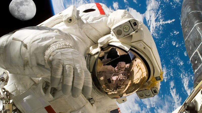 Astronaut im Weltall, im Hintergrund Erdkugel und Mond