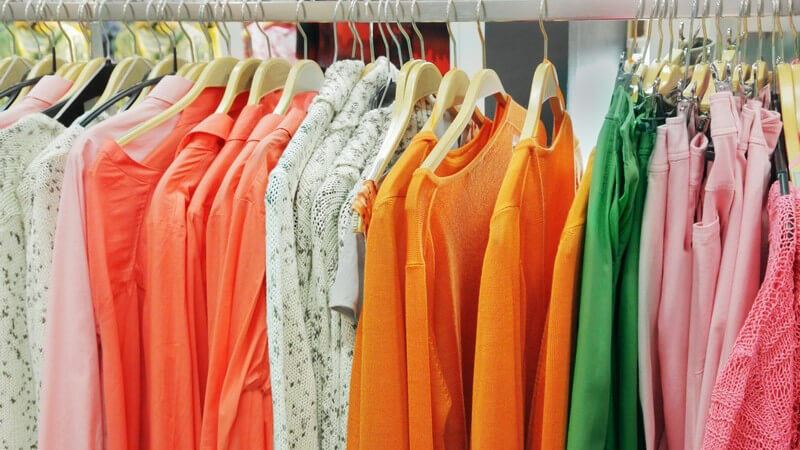 Kleiderstange in Damenboutique: Blusen und Hosen hängen an Kleiderbügeln
