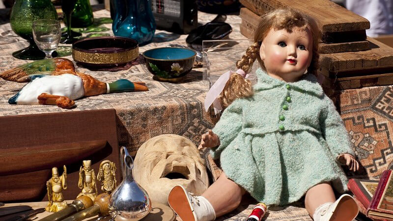 Ausschnitt Flohmarktstand mit Trödel, alte Puppe, Figuren, Bücher