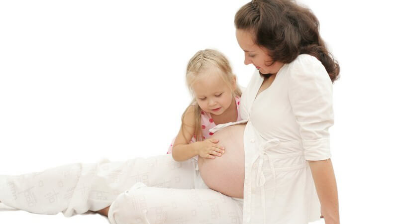 Kleines Mädchen legt ihrer schwangeren Mutter die Hand auf den Bauch