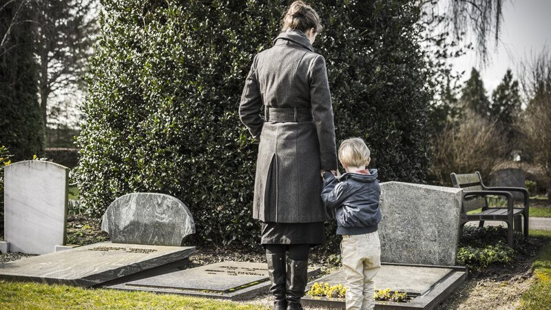 Trauer - Mutter und Sohn besuchen Grab auf dem Friedhof
