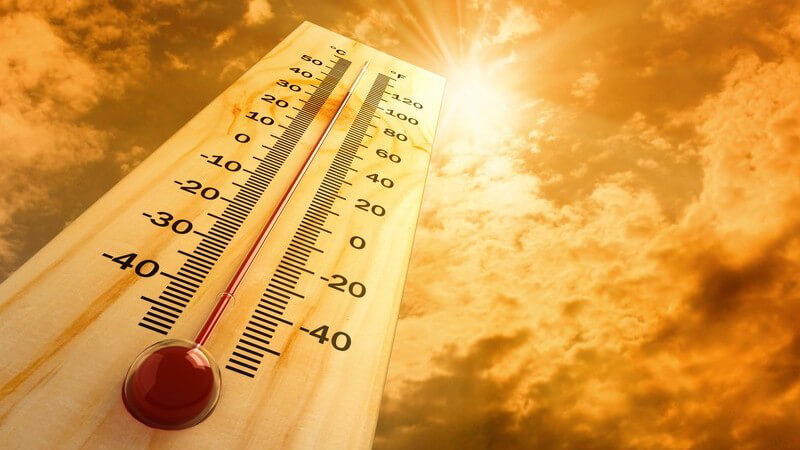 Thermometer zeigt 40 Grad Celsius an und ragt Richtung Sonne in den orangefarbenen Himmel