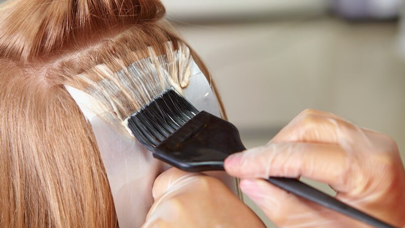 Haare einer Frau beim Friseur werden gefärbt oder coloriert