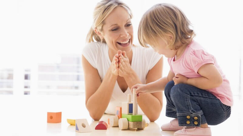 Mutter und kleine Tochter spielen mit Bauklötzen