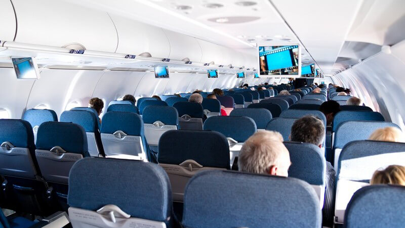 Blick aus einer hinteren Reihe durch ein Flugzeug mit blauen Sitzen