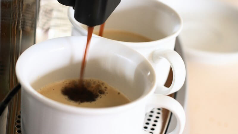 Kaffee läuft aus Kaffeemaschinen in Tassen