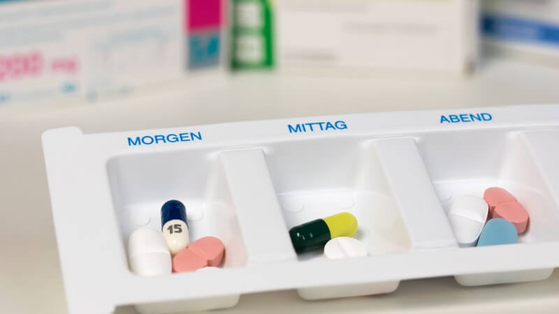 Verschiedene Tabletten für morgens, mittags und abends liegen sortiert in einer Dosierhilfe